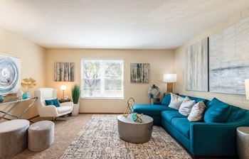 A living room with a blue couch and a rug.